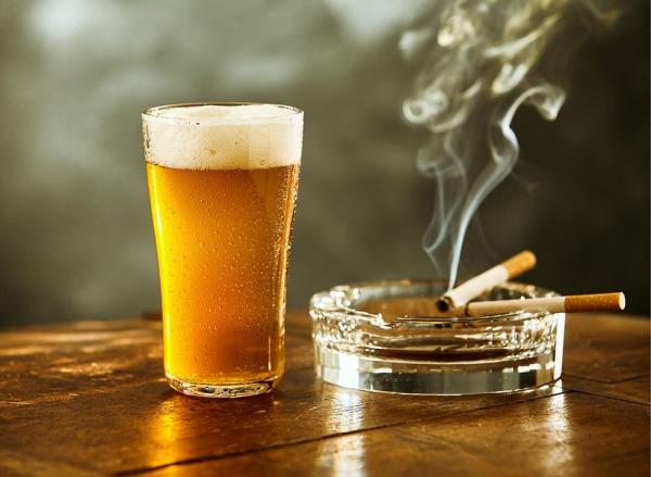 A pint of beer and a cigarette in an ashtray